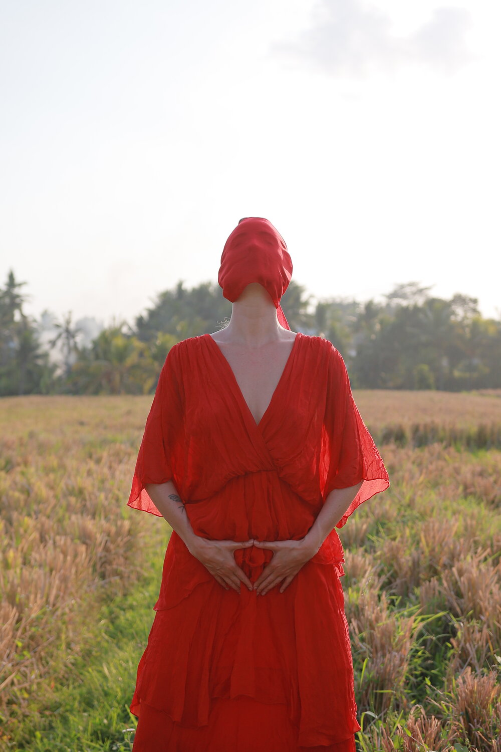 Bliss Ann in a red dress, hands resting over her womb